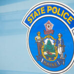 The door of a State of Maine police vehicle. The state police seal contains imagery from the Maine state flag.