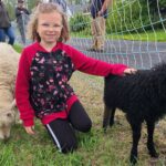 GRAND ISLE, Maine -- May 28, 2022 -- NoMa Homestead and Market Festival goer, Claire, spent most of her time in the petting zoo with the goats, sheep, and bunnies in Grand Isle on May 28. (Emily Jerkins | St. John Valley Times)